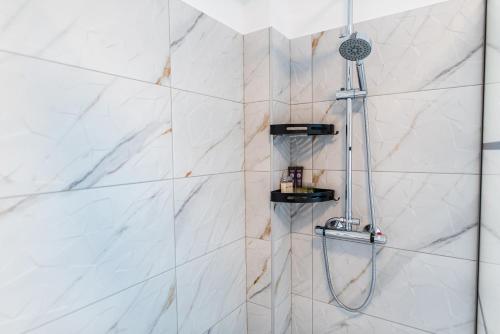 a bathroom with a shower with white marble walls at TEILOR Apartments 1 in Floreşti