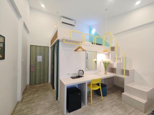 a room with a desk and a staircase with yellow chairs at Ostay Asoke Bangkok in Makkasan