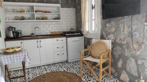 cocina con armarios blancos, mesa y sillas en Stone Cottage garden, terrace sea and forest view en Marmaris