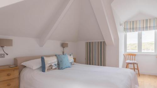 a bedroom with a white bed and a chair at Castle House - Penthouse in Polruan