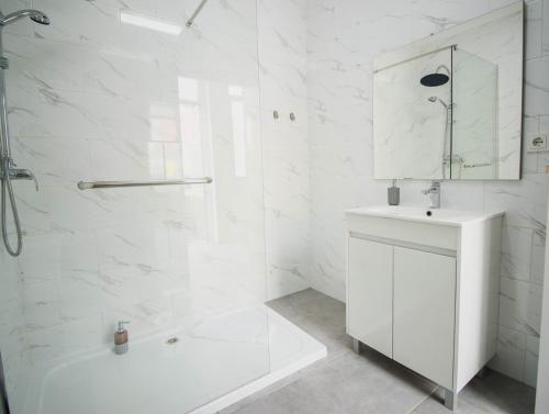 a white bathroom with a shower and a sink at Casa das Vigas II in São Mamede de Infesta