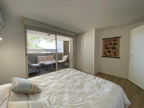 Un dormitorio con una gran cama blanca y una ventana en T3 bis bord du canal du midi piscine, en Homps