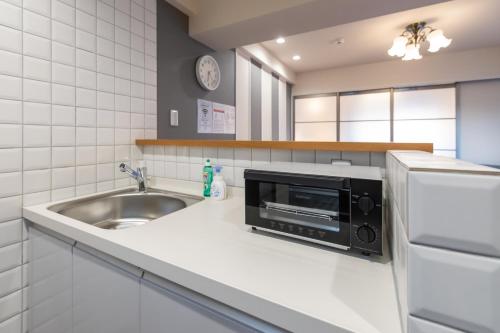 a kitchen with a sink and a microwave at H2H Dotonbori in Osaka