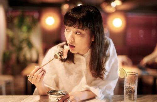 a woman sitting at a table eating food with a fork at Hotel She, Kyoto in Kyoto