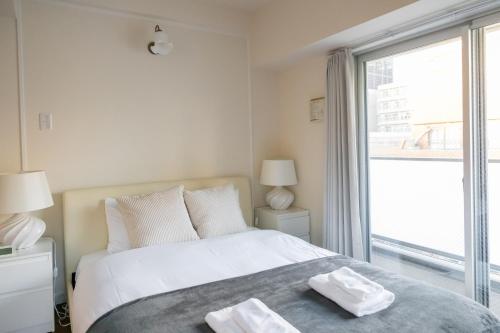 a bedroom with a bed and a large window at H2H Dotonbori in Osaka