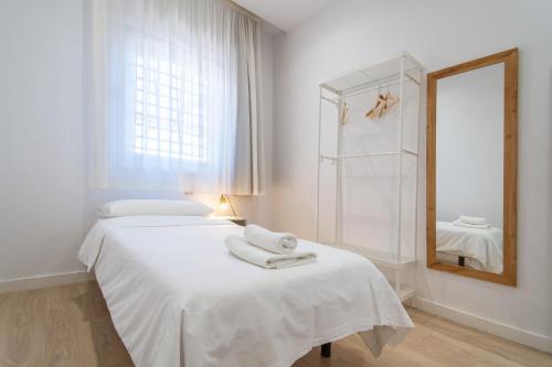 a white bedroom with two beds and a mirror at Calixto Fernández de la Torre 2 in Valladolid