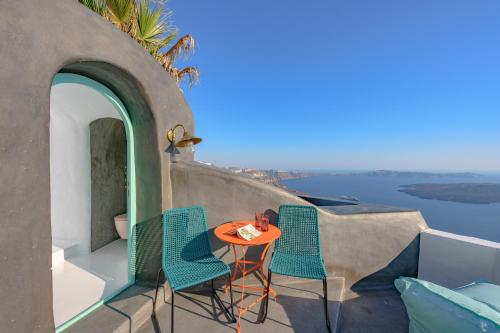 a table and chairs on a balcony with a view of the water at Sophia Luxury Suites in Imerovigli