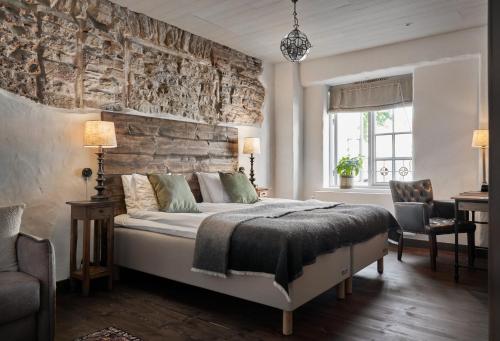 een slaapkamer met een bed met een stenen muur bij Hotel Helgeand Wisby in Visby