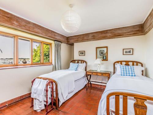 two beds in a room with a window at Pass the Keys Historic Waterfront Home in Bosham in Bosham