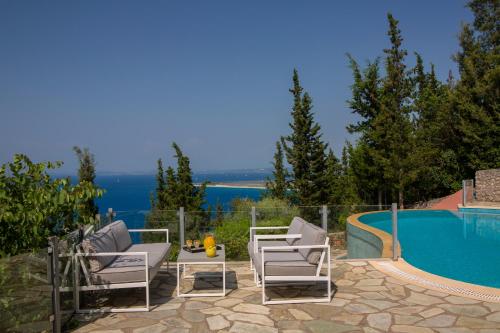 a patio with two chairs and a swimming pool at Boutique Villa Andronice in Tsoukaladhes