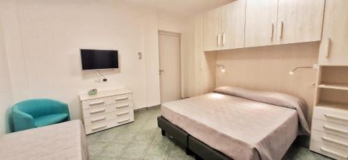 a bedroom with two beds and a tv and a chair at Bilocale Gemma in Arbus