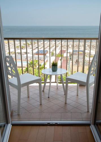 two chairs and a table on a balcony with the beach at Hotel Mon Cheri in Riccione