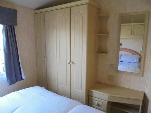 a bedroom with a bed and a dresser and cabinets at Waterside: Waterside Salisbury:- 6 Berth Large Wrap Around Veranda in Ingoldmells