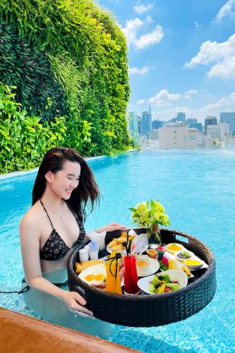 a woman sitting in a pool with a tray of food at Paradise Saigon Boutique Hotel & Spa in Ho Chi Minh City