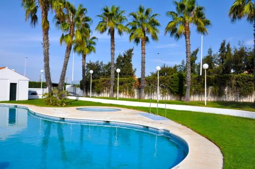 a swimming pool in a park with palm trees at Casa Lea in Islantilla