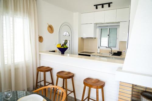 a kitchen with wooden stools and a counter top at Meneou Houses by the Sea in Larnaka