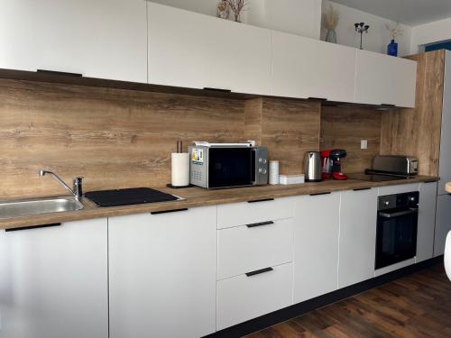 une cuisine blanche avec un évier et un micro-ondes dans l'établissement Goldfinger- appartement Malo-les-Bains, à Dunkerque