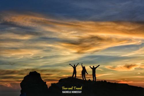 dos personas de pie en la cima de una montaña al atardecer en Nachelle Homestay en Berastagi