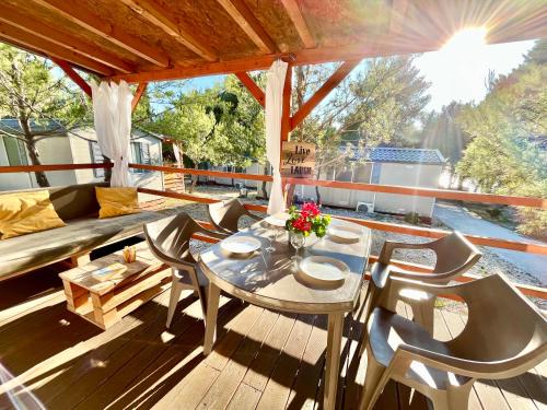 a patio with a table and chairs on a deck at Mobilehome Adams Glamping - Camp Adriatic in Primošten