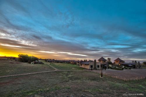 a view of a field with houses and a sunset at Emoya Basotho Lodge in Bloemfontein