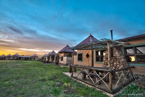 a group of lodges in a field with the sunset at Emoya Basotho Lodge in Bloemfontein