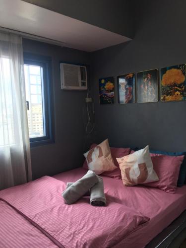 a bed with pink sheets and pillows and a window at Simple & Cozy 1 Bedroom US Embassy, Roxas Blvd, Ermita, Manila in Manila