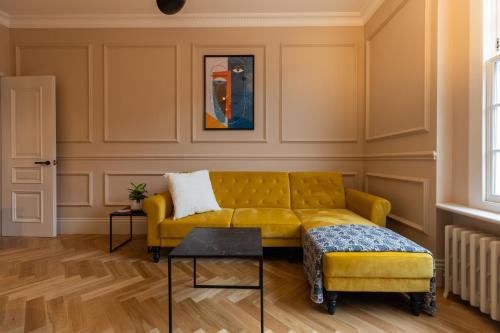 a yellow couch and a stool in a room at Boutique Apartment in Camden road in London