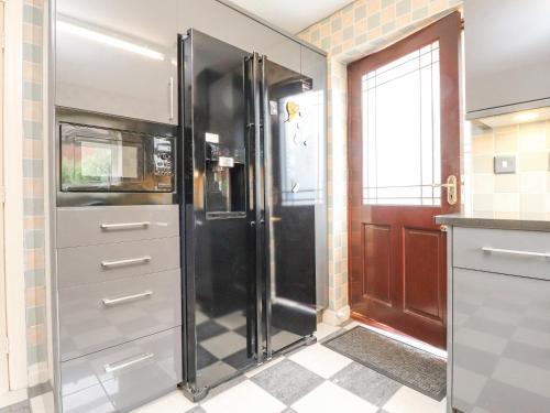a kitchen with a refrigerator and a door at 23 Wolsey Close in Thornton