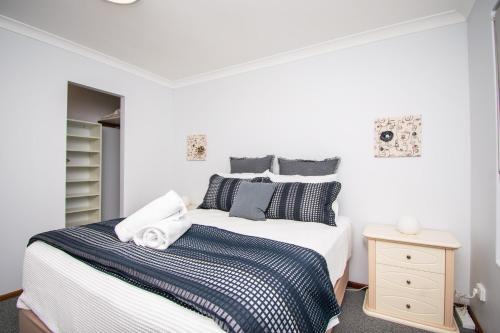 a bedroom with a bed with blue and white sheets at Gairdner Cottage - something a bit different! in Albany