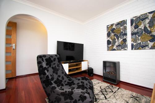 a living room with a chair and a tv at Gairdner Cottage - something a bit different! in Albany