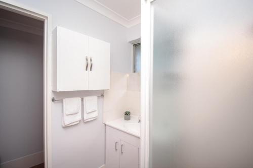 a white bathroom with a sink and a mirror at Gairdner Cottage - something a bit different! in Albany