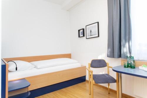 1 dormitorio con cama, escritorio y silla en JUFA Hotel Garni Stubenberg am See, en Stubenberg