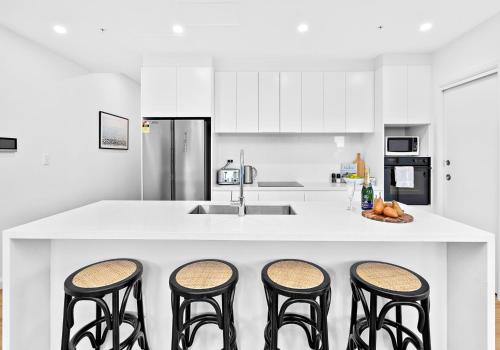 a kitchen with a counter with four bar stools at Sea Dreams in Gerringong