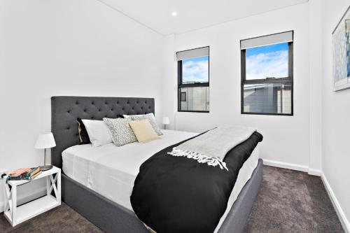 a bedroom with a large bed and two windows at Sea Dreams in Gerringong