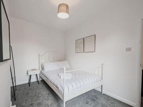 a white bed in a room with a white wall at Valley Park House - By Sigma Stays in Crewe