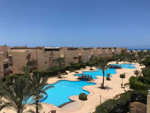 an aerial view of a resort with three pools at شاليه ارضي بجنينه علي البسين مباشرة in Dawwār al Ḩajj Aḩmad
