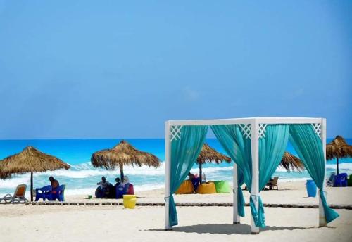 einen Pavillon am Strand mit Leuten, die unter Sonnenschirmen sitzen in der Unterkunft شاليه ارضي بجنينه علي البسين مباشرة in Dawwār al Ḩajj Aḩmad