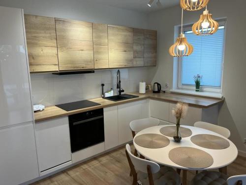 una cucina con tavolo e una cucina con armadietti bianchi di Apartamenty Ustronie Morskie31B4 a Ustronie Morskie