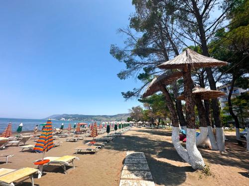 a beach with chairs and umbrellas on the beach at Frojd Kune Resort & Beach Hotel in Shëngjin