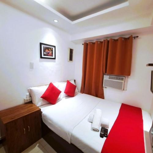 um quarto com uma cama com almofadas vermelhas em Makati Poblacion Hotel em Manilla