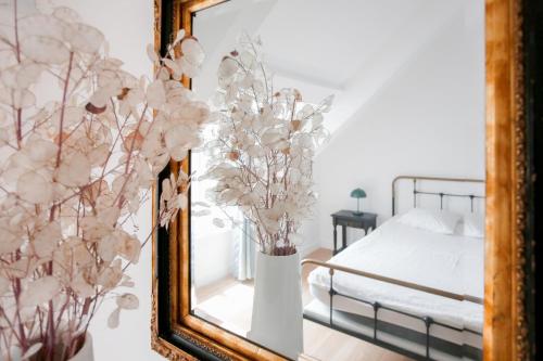 - un miroir avec un vase de fleurs dans la chambre dans l'établissement 1km plage du Prieuré - Dinard- Cocon pour 2, à Dinard