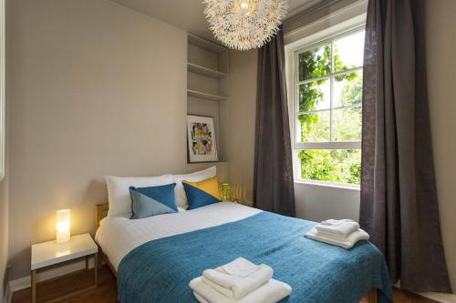 Un dormitorio con una cama azul con toallas. en Camden Apartment By Morethanstays, en Londres