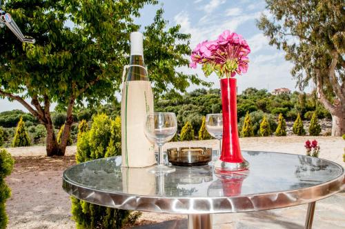 - une table en verre avec une bouteille de vin et un vase avec des fleurs dans l'établissement Alexia Ferentinou, à Fiskardho