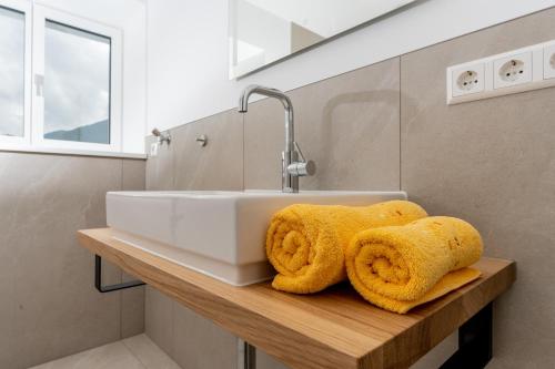 a bathroom with a sink and towels on a wooden shelf at Ferienwohnungen Hartl in Spitz