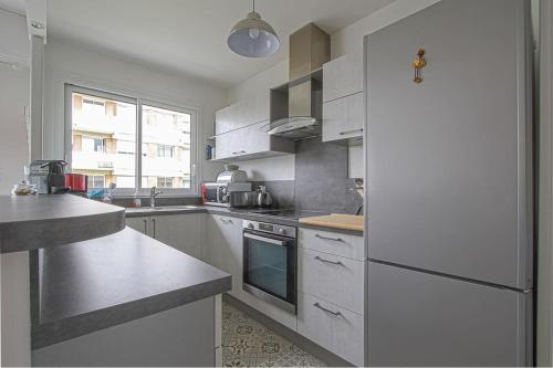 a kitchen with white appliances and a large window at Appt agréable avec balcon au sud-ouest de Caen in Caen
