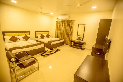 Cette chambre comprend deux lits et une télévision. dans l'établissement Hotel Royal Elite Madurai, à Madurai