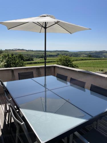 a table with an umbrella on a balcony at Le Cocon et le panorama des Hautes-Côtes in Fussey