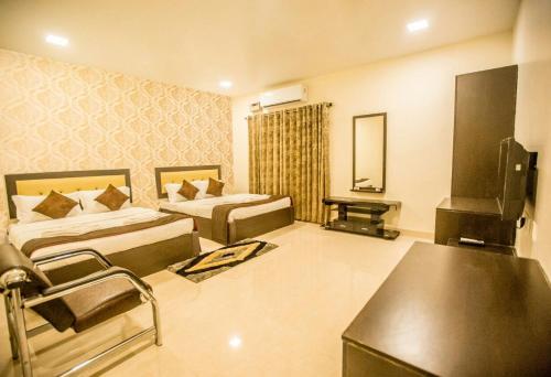 a hotel room with two beds and a television at Hotel Royal Elite Madurai in Madurai