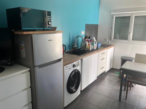 eine Küche mit einem Kühlschrank und einer Waschmaschine in der Unterkunft Petit studio proche de l’aéroport Charles de Gaulle in Villepinte