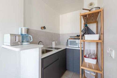 a small kitchen with blue cabinets and a shelf at Studio cosy, 4Pers, wifi, proche Disney, Parking - Fairytale Factory in Bussy-Saint-Georges